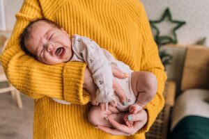 Mamá consolando en brazos a su bebé que llora