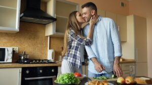 Pareja sonriente preparando una comida saludable en casa